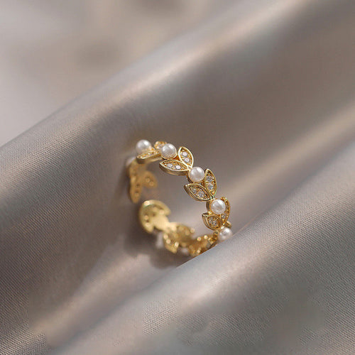 Gold leaf wheat pearl crystal ring resting on gray satin