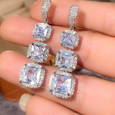Product view showing three-tier square halo long drop earrings