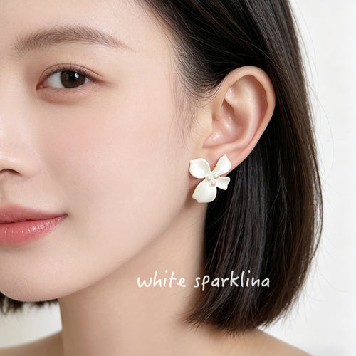 White-painted-flower high-luster-pearl studs shown worn on an ear.