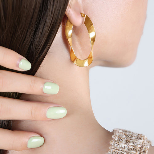 Model wearing gold twisted geometric open hoop earring side profile
