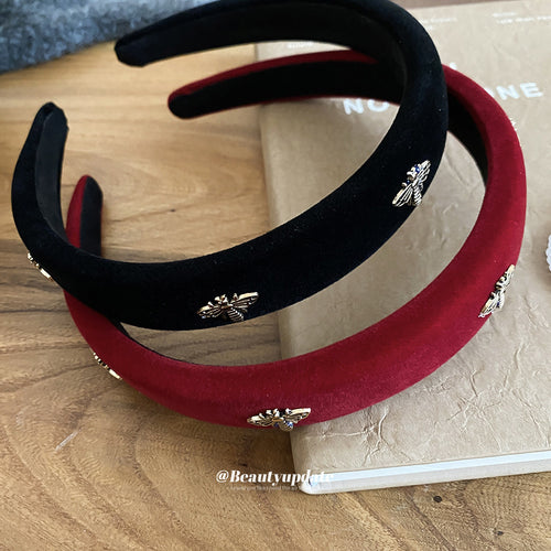 Black and red velvet bee charm headbands stacked on book