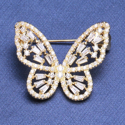 Front view of small gold openwork butterfly brooch against a white background.