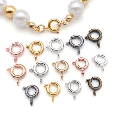 Metallic spring clasp jewelry findings arranged on a light background