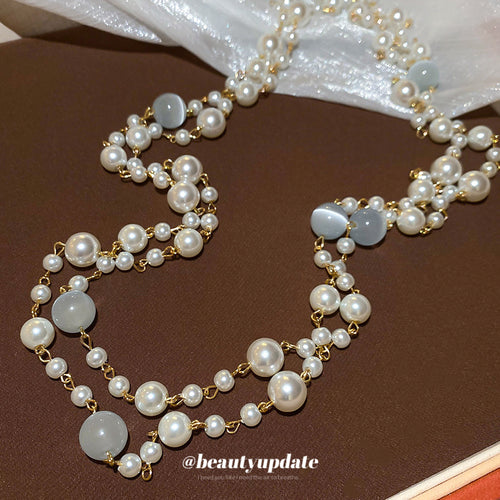 Two uneven strands mixing white pearl-look beads and gold-tone links shown in a styled close-up