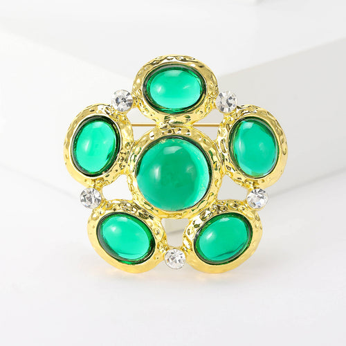 Angled display of the oval stone cluster brooch on a white surface