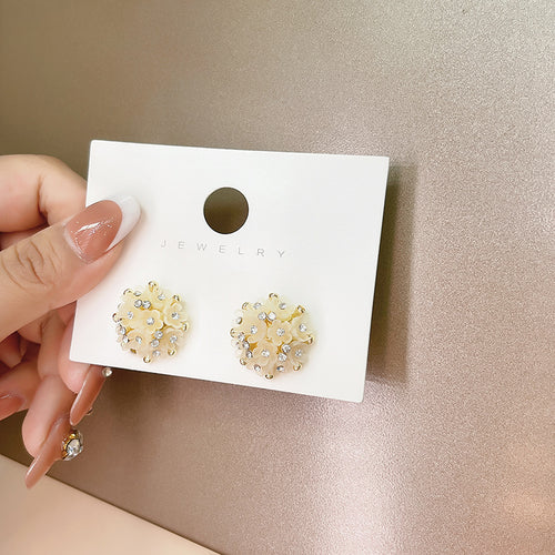 Studs on white card labeled Jewelry held in hand
