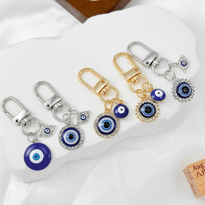 Five evil eye charm keychains with D-ring swivel clasps in gold and silver tone arranged together