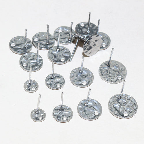 Detail view of round textured discs, straight posts, and hanging holes in gold and silver tones