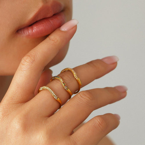 Model wearing stacked gold wave pave zircon rings on fingers