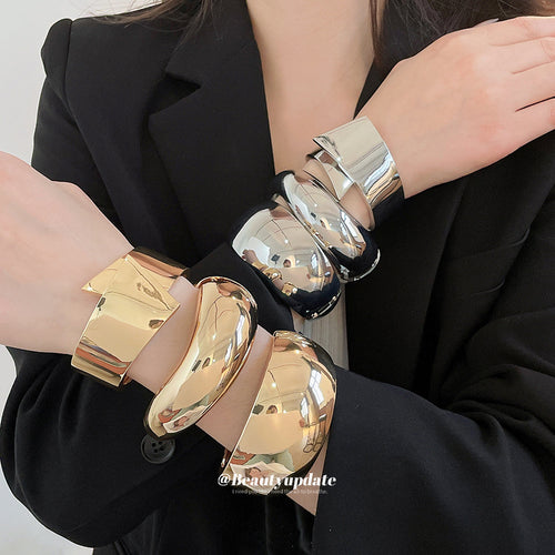 Gold and silver polished metal bangles stacked on both wrists