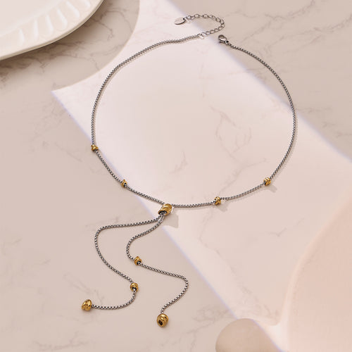 Two-tone steel and gold pull Y necklace flat on white