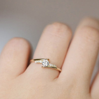 Gold crossed band clear stone ring worn on finger close-up