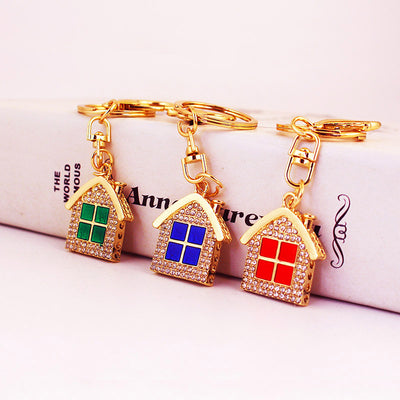 Three gold tone house keychains display green, blue, and red window panels.
