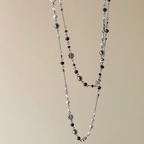 Two graduated bead strands with small flower accents shown in a styled close-up