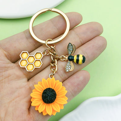 Image 1 showing a person holding a flower and bee keychain.