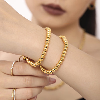 Two gold bead bracelets stacked on wrist