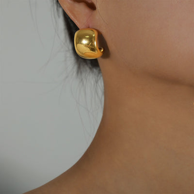 Gold chunky C-shape hoop earring worn on ear close-up