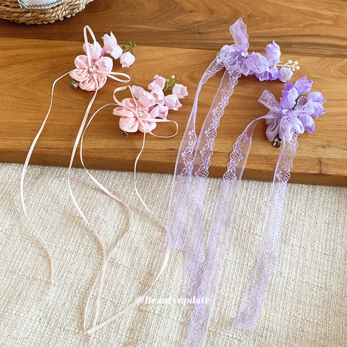 Pink and purple fabric flower duckbill clips with long ribbons on wooden surface