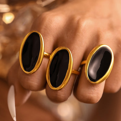 Three gold oval black oil drip open rings worn across fingers
