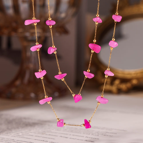 Close-up of pink stone gold chain necklace on white background