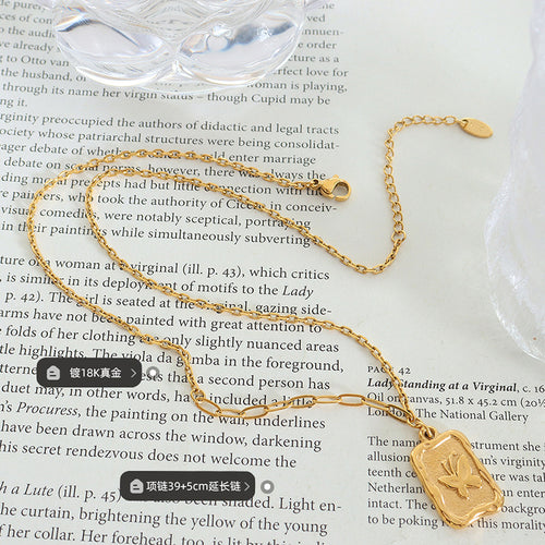 Gold necklace laid on book page showing clasp and labels