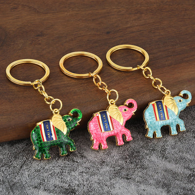 Three gold-tone key rings display green, pink, and light blue elephant charms.