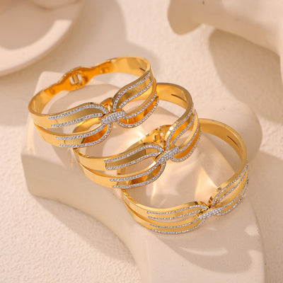 Three gold geometric crystal cuff bangles stacked on beige stand