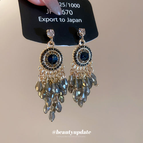 silver tone blue crystal chandelier drop earrings with metal tone details shown in an on-ear styling view