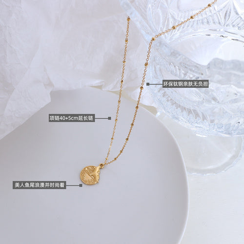 Gold mermaid tail disc necklace flat lay with length and material callouts