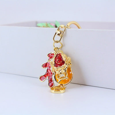 Gold-tone toad keychain standing against white boxes with a red character and coin dangle.
