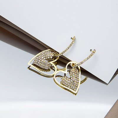 Gold heart drops hanging over reflective surface