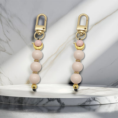 Two matching pink and ivory bead charms stand on a marble display.