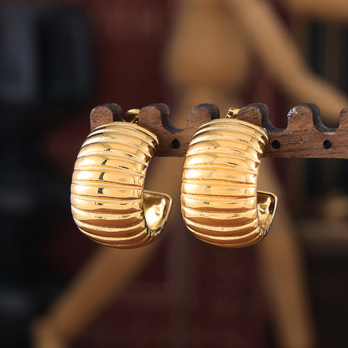 Pair of gold ribbed C-shape hoops on wooden earring stand