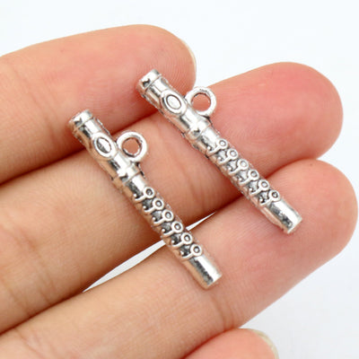 Antique silver-tone flute charm with two side loops in a group view on a white background