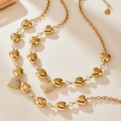 Gold heart station necklace coiled close-up on cream surface