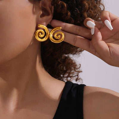 Model wearing large gold spiral swirl stud earrings