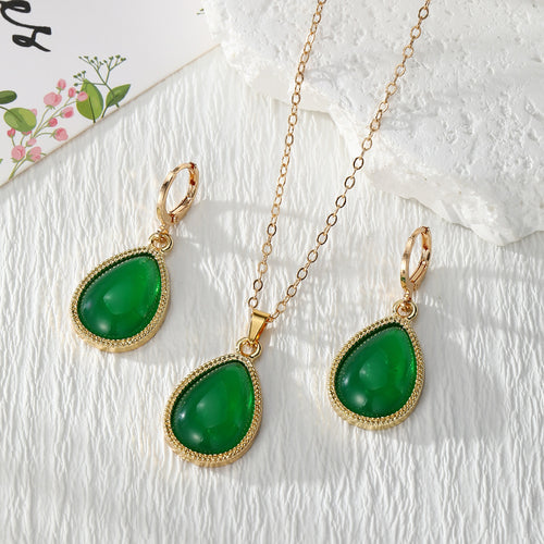 Green teardrop gold frame hoop earrings and necklace set on white cloth