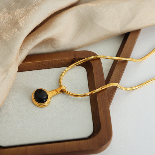 Gold black oval stone pendant draped across wooden trays