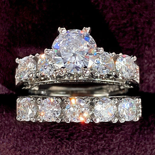 Stacked silver dual CZ engagement rings close-up on purple velvet
