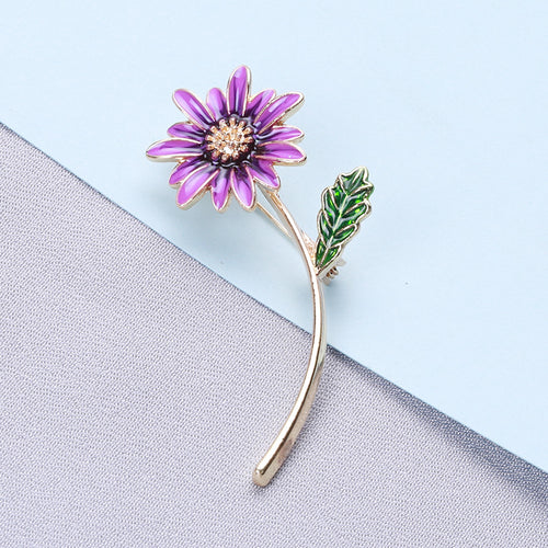 Purple daisy flower brooch on blue and grey fabric background