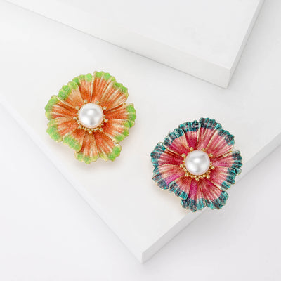 Front view of a round layered enamel flower centered with a white pearl