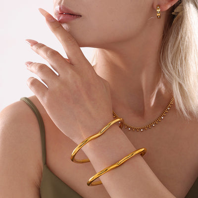 Model wearing two gold heart closed bangles stacked on wrist
