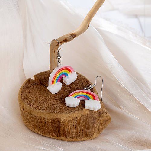 Rainbow cloud earrings on wood stump one hanging one lying down