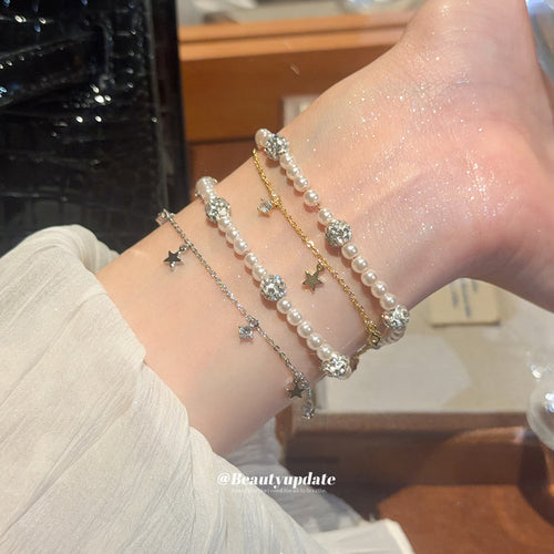 Wrist stacked with gold and silver pearl star bracelets