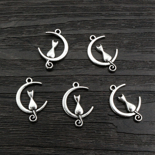 Finish comparison of cat sitting on crescent moon metal charms in antique silver tone