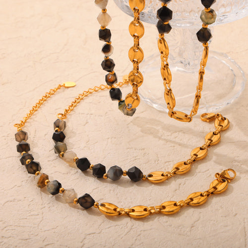Close flat lay of gold mariner links mixed with faceted stone bead strands