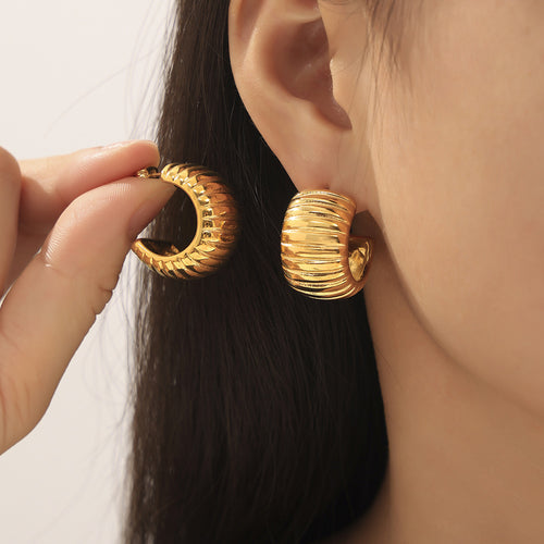 Model holding gold ribbed C-hoop beside matching worn earring