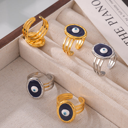 Gold and steel evil eye open rings in beige jewelry tray multi angle