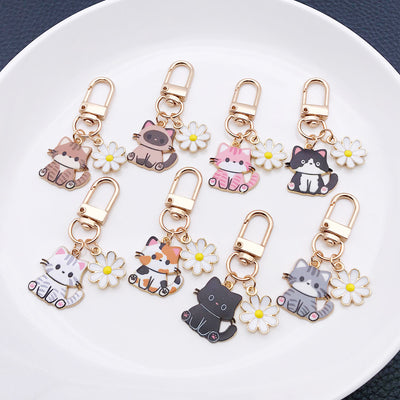 Front product photo of mixed cat and white daisy enamel clip keychain eight-style showing the pictured design arrangemen