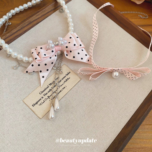 Styled wear view of 粉色波点缎带颈链 showing pink dotted ribbon bows paired with either a ribbon band or a white pearl strand
